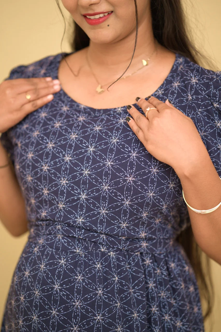 Woman wearing a blue dress with white geometric pattern against a neutral background
